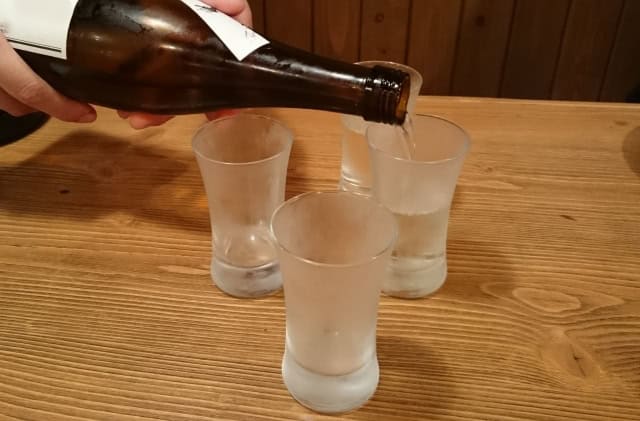 Sake being poured into a glass for serving at the right temperature