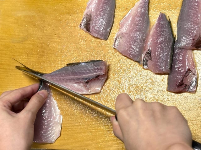 Filleting fish on a wood cutting board with a Japanese knife