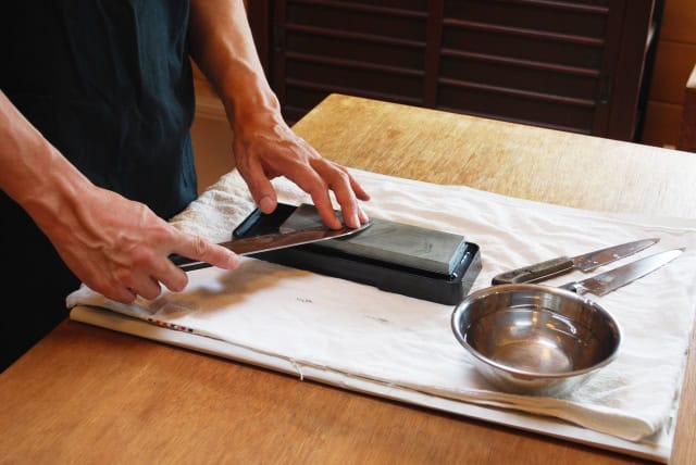 Whetstone, water container, and knife laid out for sharpening