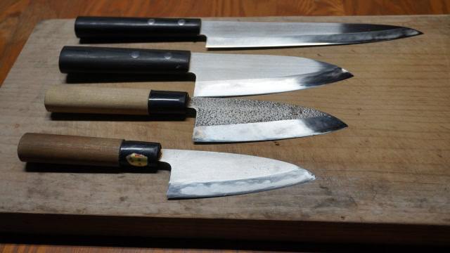 Four Japanese gyuto knives from different brands arranged together