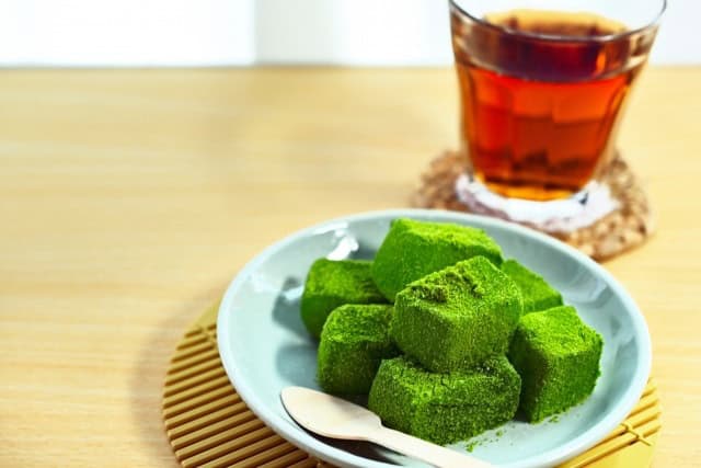 Matcha warabi mochi coated in green tea powder on a plate
