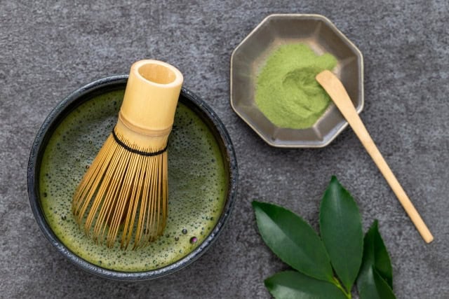 Matcha bowl, bamboo whisk, powder, and scoop arranged flat-lay style