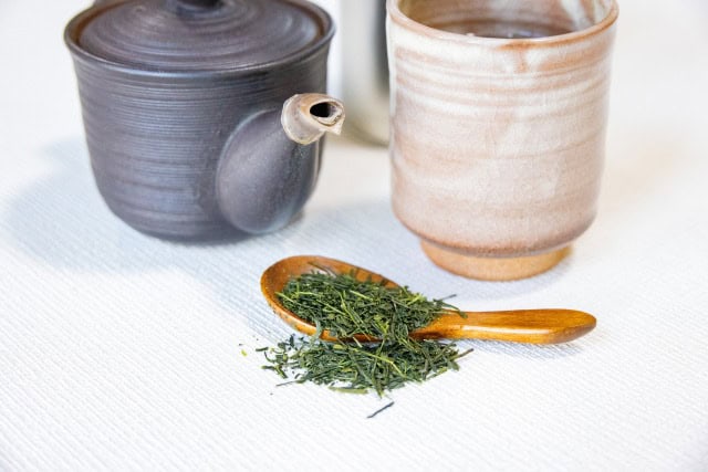 Japanese teapot, cup, and loose leaf sencha on a wooden spoon