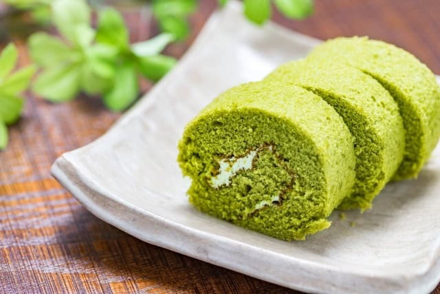 Sliced matcha roll cake showing cream filling on a plate