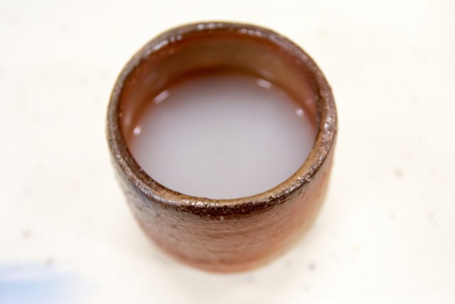 Milky white nigori sake served in a ceramic cup