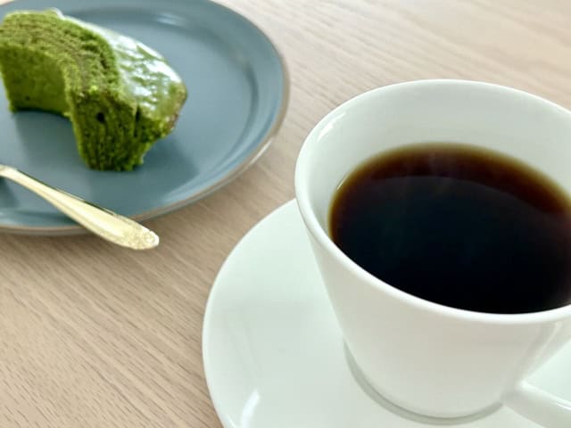 Matcha chiffon cake beside a cup of black coffee