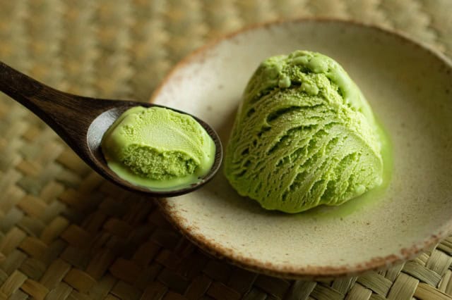 Scoop of matcha ice cream on a plate with wooden spoon