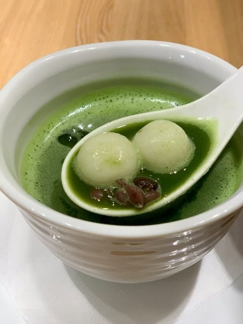 Matcha zenzai soup with mochi balls and red beans in a bowl