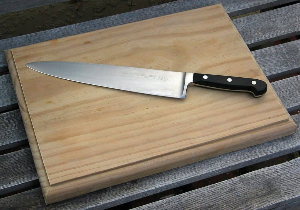 A kitchen knife resting diagonally on a wooden cutting board