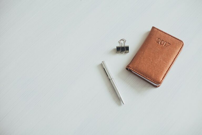 Brown notebook, pencil and binder clips on a desk