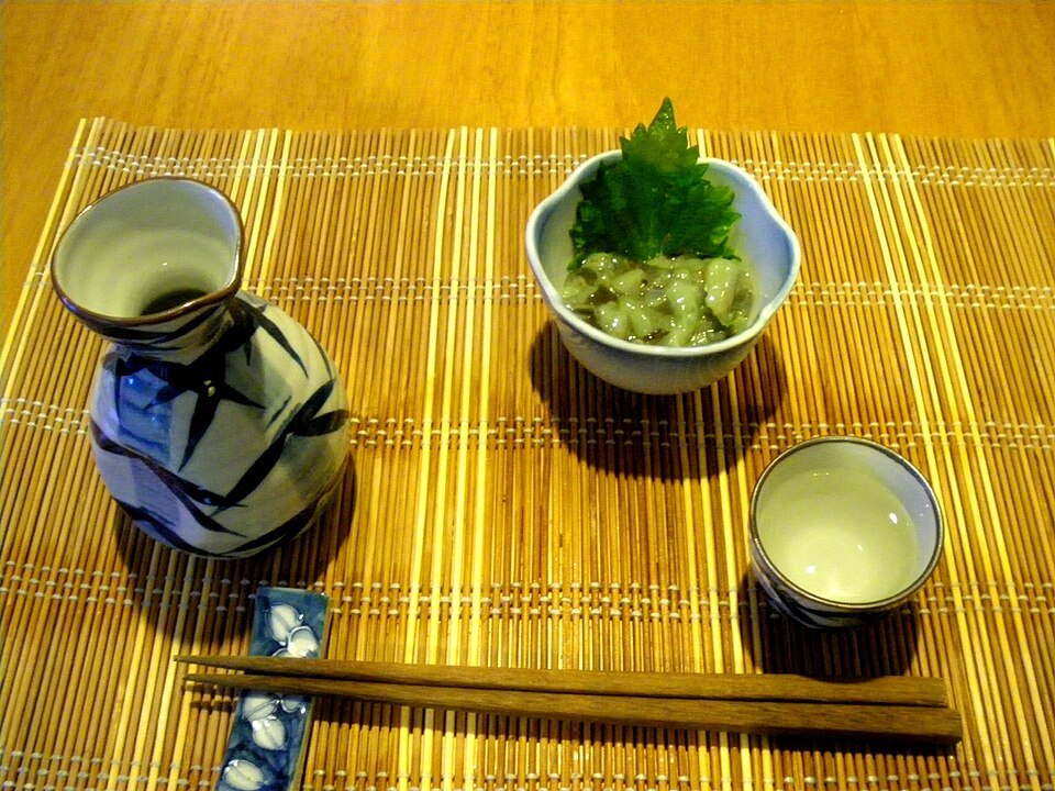 Sake flask and cup served beside takowasa, an octopus and wasabi dish