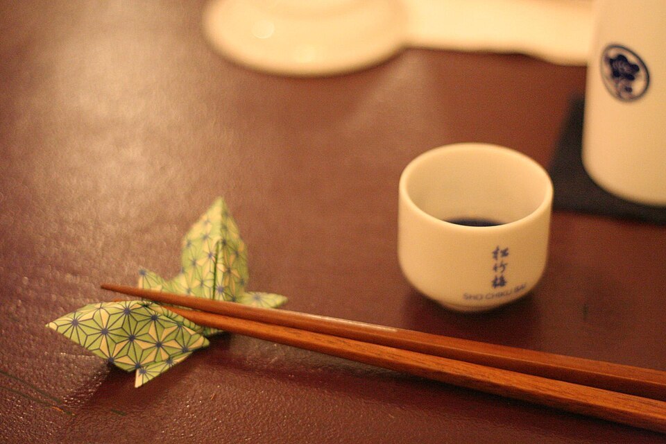 Sake flask, cup and chopsticks arranged on a table