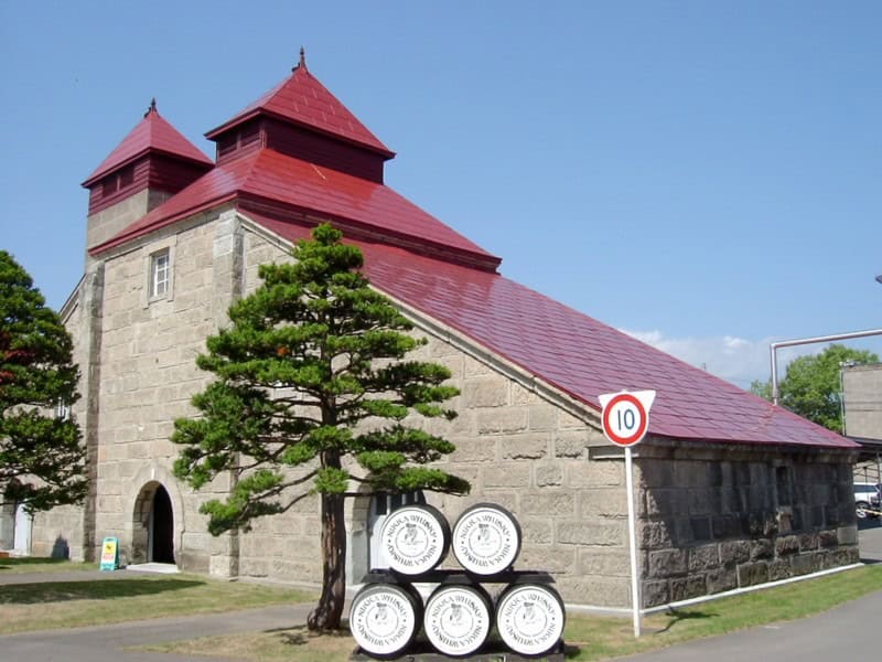 Entrance to Nikka Yoichi Distillery with red roofs and barrels